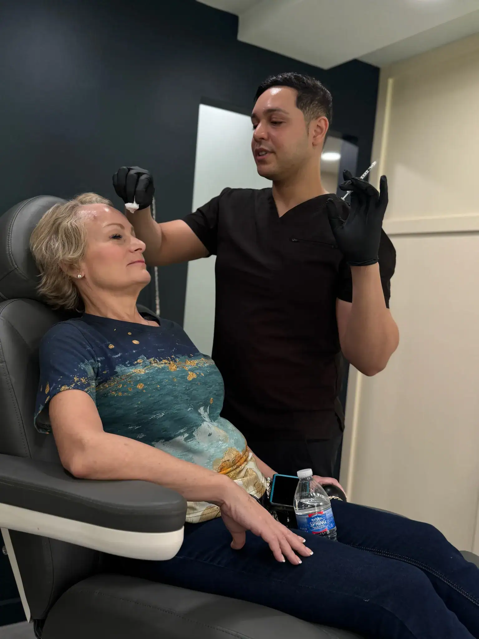 Healthcare professional performing a cosmetic injection on a woman's forehead.