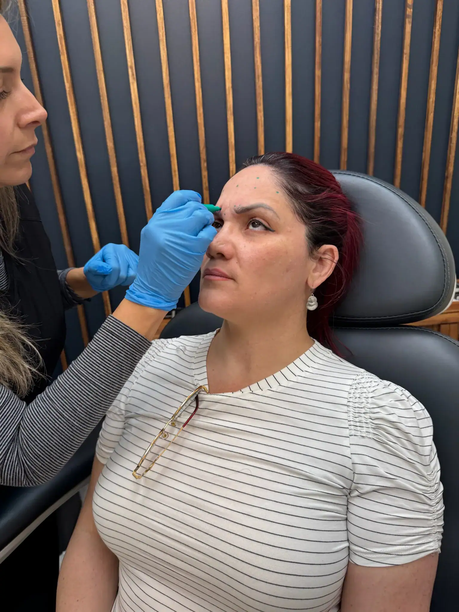 A woman receiving a Botox injection in her forehead at a clinic.