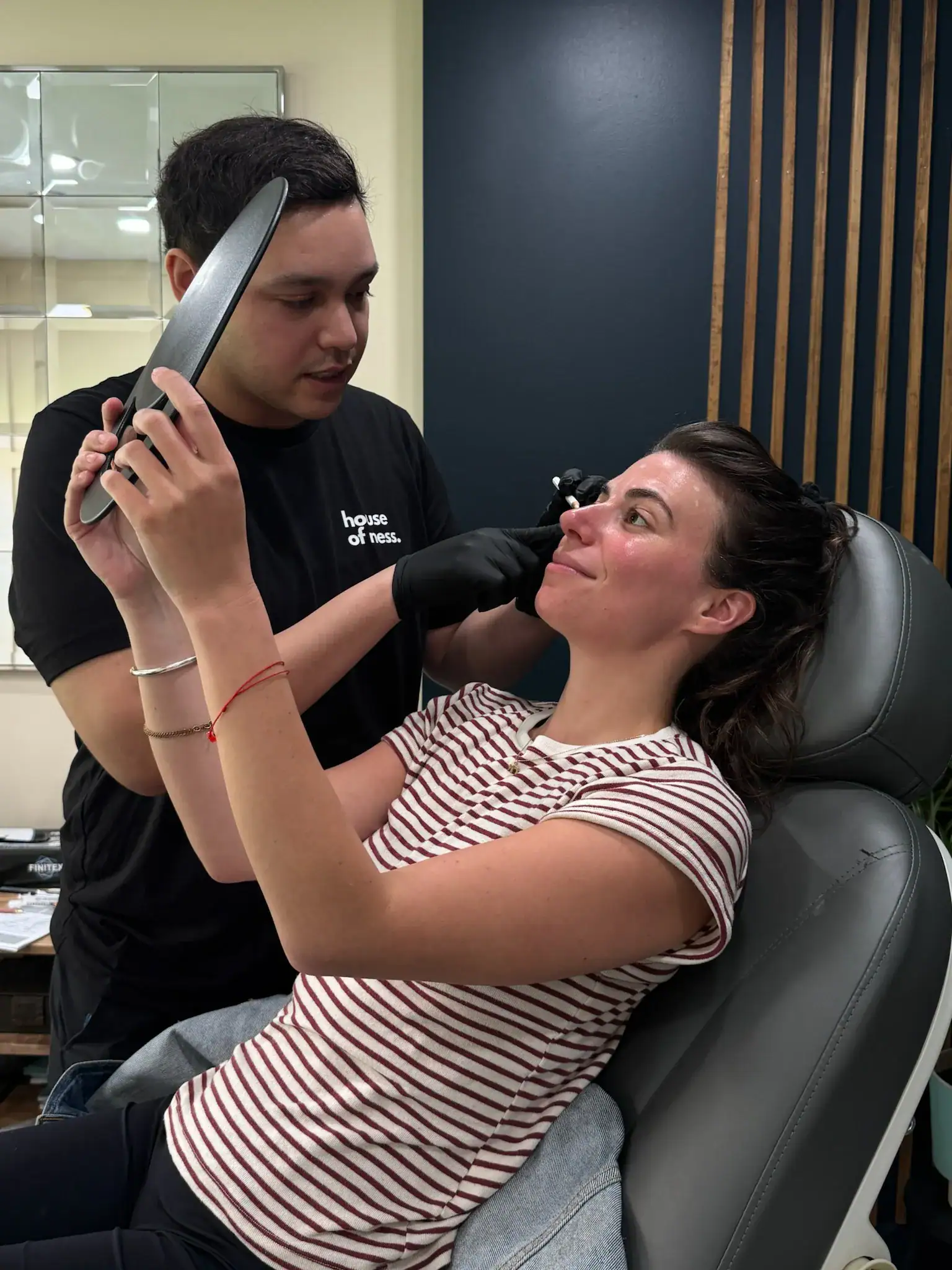Person receiving nose bridge piercing consultation in a clinic.