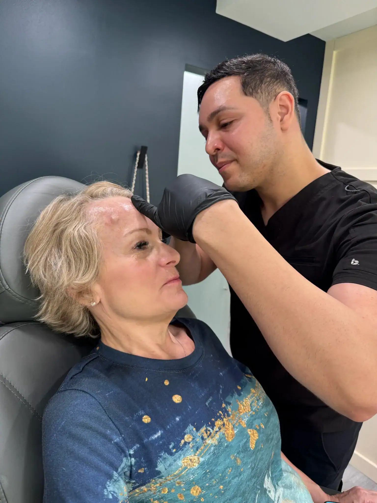 Practitioner administering Botox to a woman's forehead in a clinic.